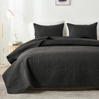 Black embossed quilt set on bed