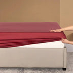 Fitting burgundy bamboo sheet on mattress
