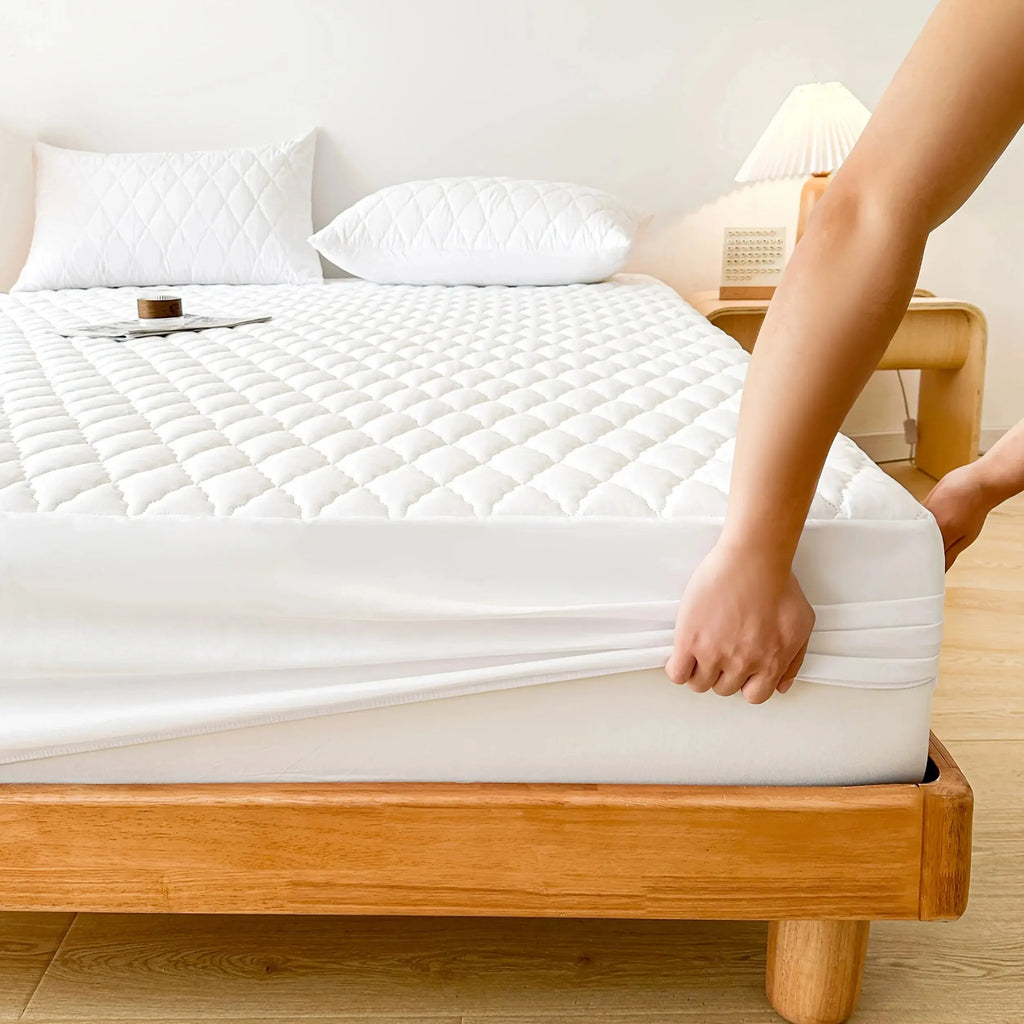 Fitting white quilted mattress pad on bed