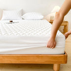 Fitting white quilted mattress pad on bed