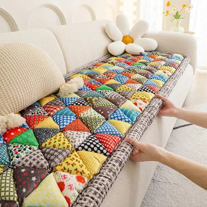 Hand placing quilted patchwork couch cover on sofa seat