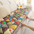Hand placing quilted patchwork couch cover on sofa seat