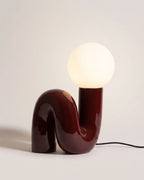 Red sculptural table lamp with glass globe