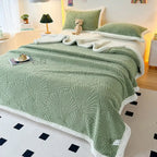 Sage green embossed fleece blanket on bed