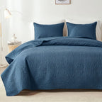 Teal blue embossed quilt set on bed