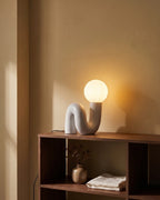 White sculptural lamp on bookshelf