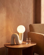 White sculptural lamp on side table by sofa