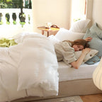 Woman relaxing on white cotton bedding